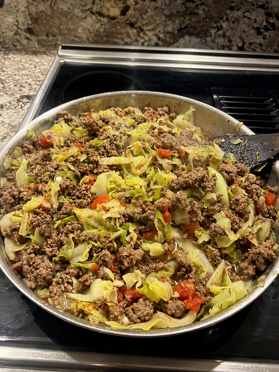 Beef cabbage stew with tomatoes cooking in a large skillet.