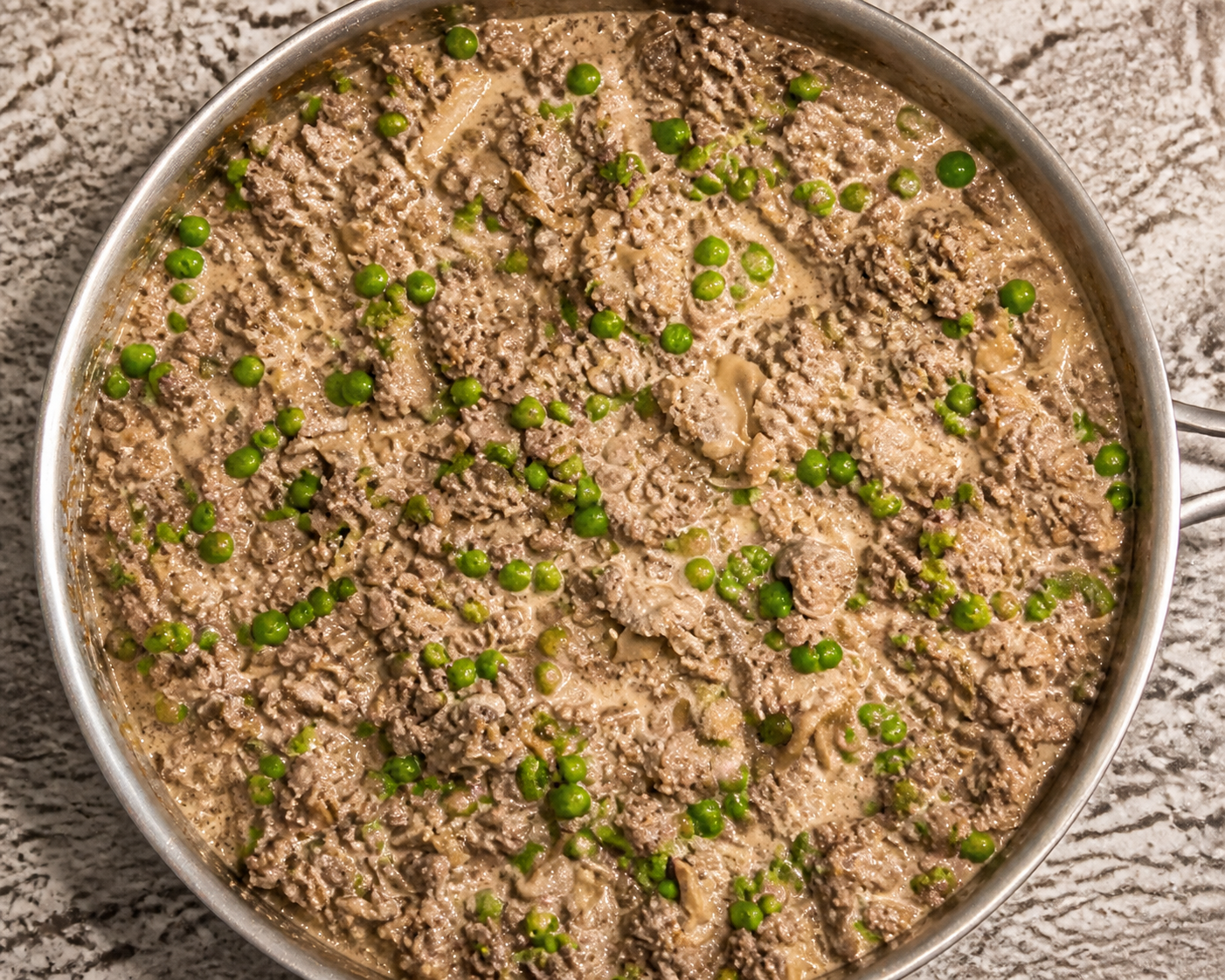 Creamy beef stroganoff skillet with ground beef, mushrooms, and peas.