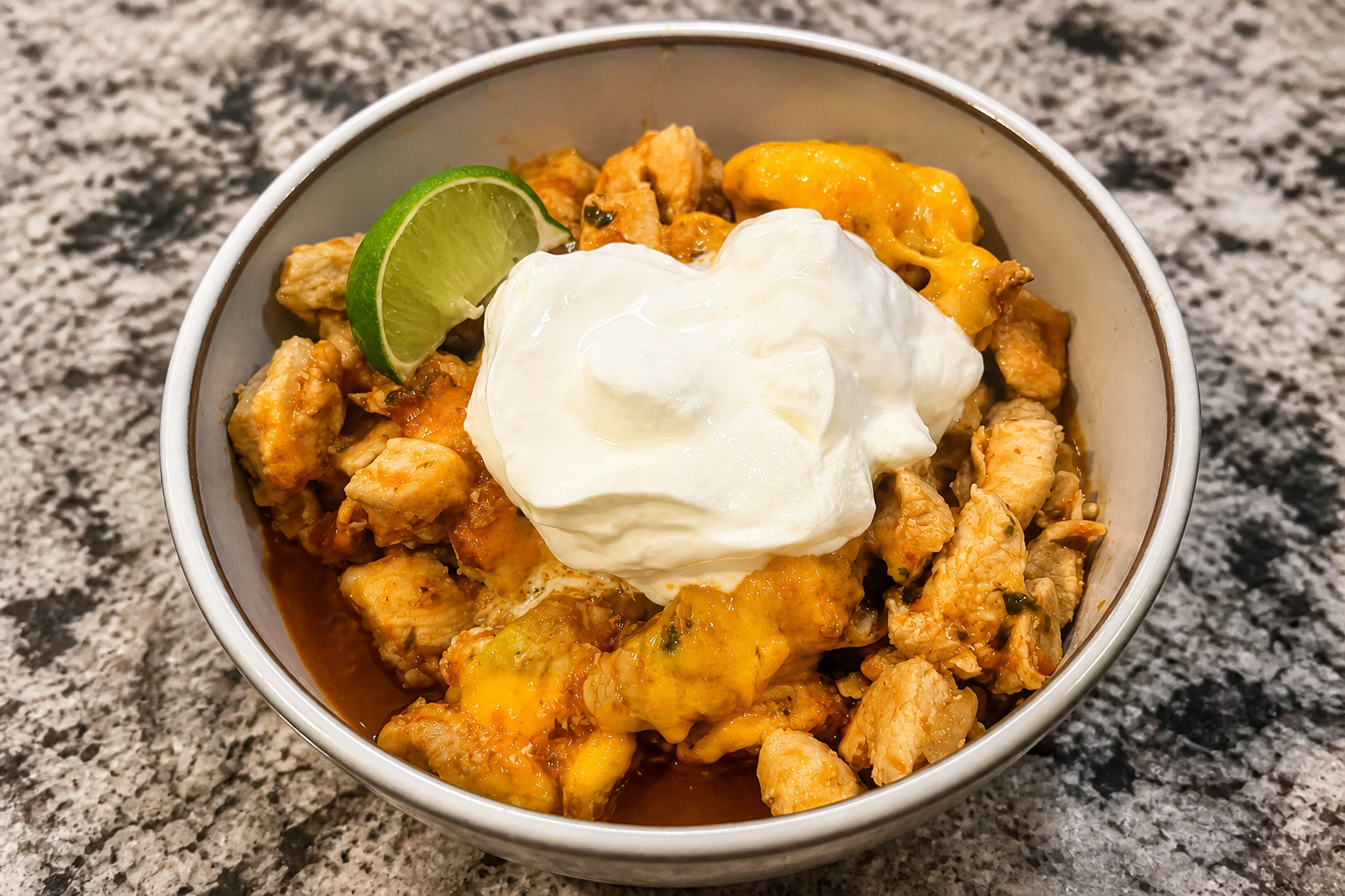 Chicken enchilada casserole with melted cheddar, sour cream, and lime.