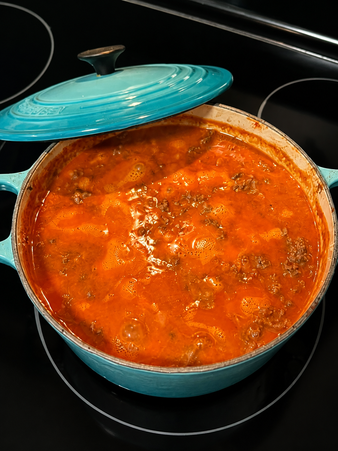 Hamburger Healthier simmering with ground beef, pinto beans, and tomato sauce in a turquoise Dutch oven.