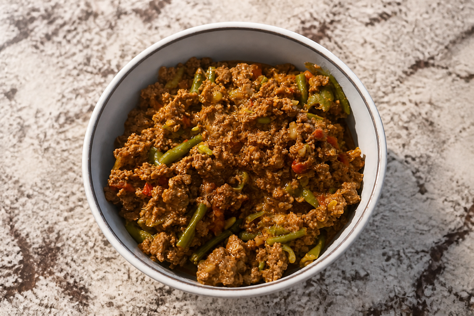 Lubia Polo made with ground beef, green beans, tomatoes, and Persian spices in a bowl.